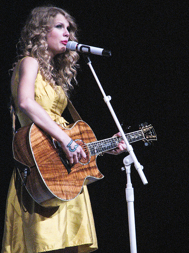 Taylor Swift perfomance onstage in a yellow dress