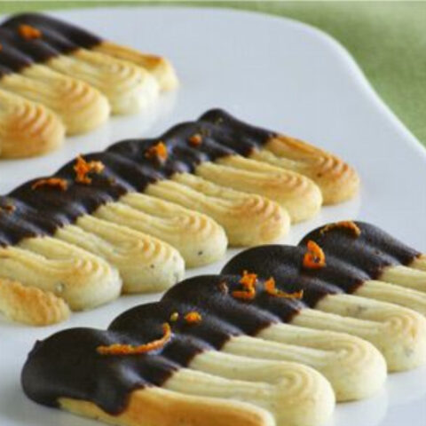 Orange-Flavored Spritz Sable Cookies dipped in Dark Chocolate